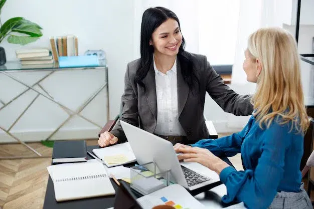 a woman comforting another infront of a laptop.webp