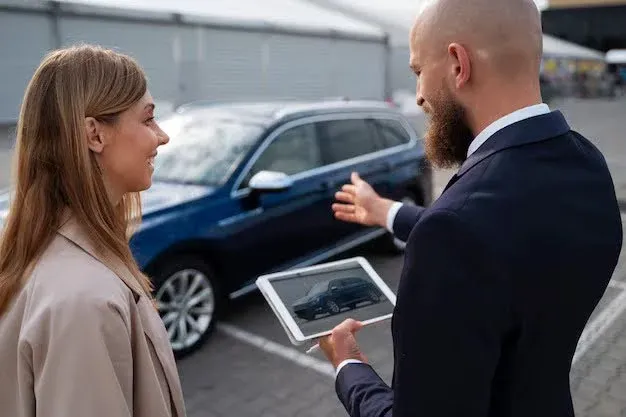 car salesman showing car to woman.webp