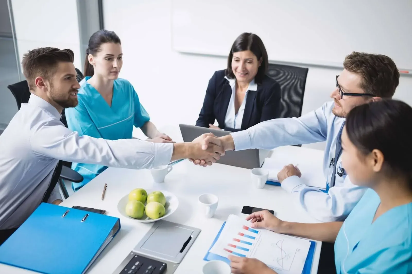 group of people discussing something on a table with two of them shaking hands.webp