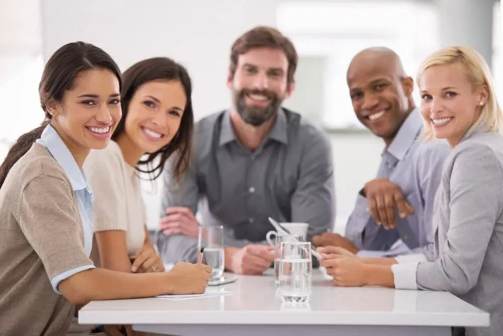group of people sitting on a table smiling at camera.webp