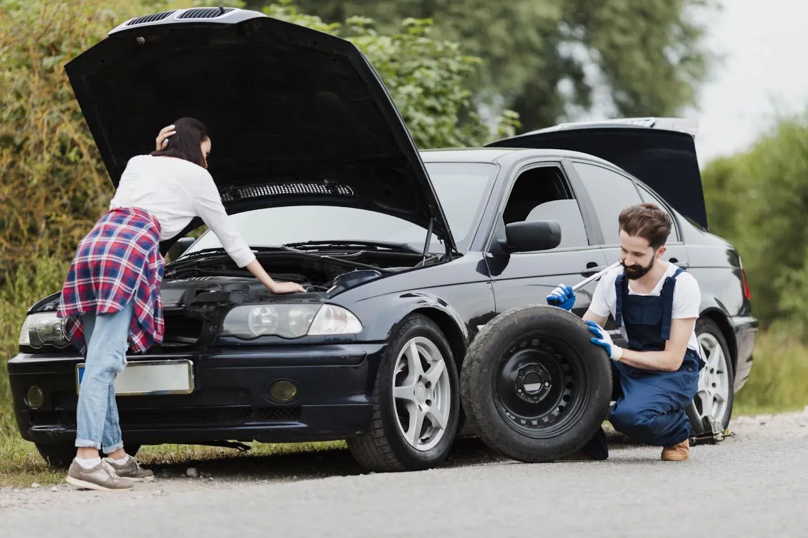 women with faulty car while mechanic repairing her car tyre.webp